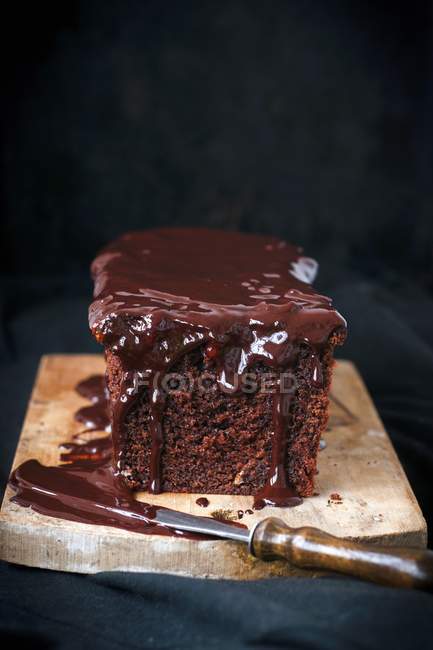 Closeup view of cake with chocolate spread and knife on wooden board — Stock Photo