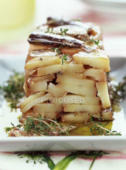 Patatas prensadas con tomillo sobre plato blanco sobre mesa - foto de stock
