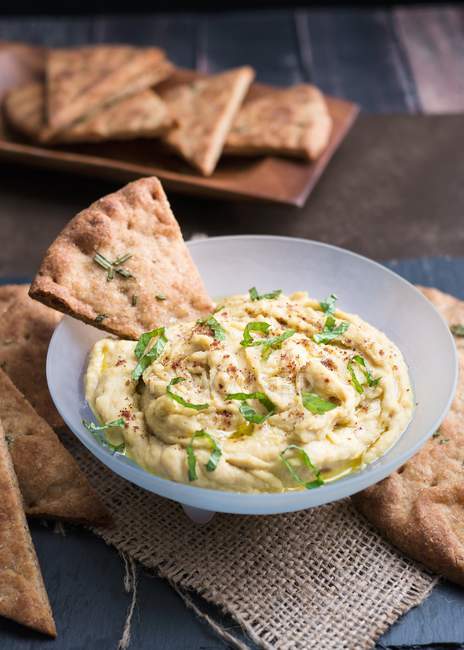 Hummus with flatbread crisps — Stock Photo