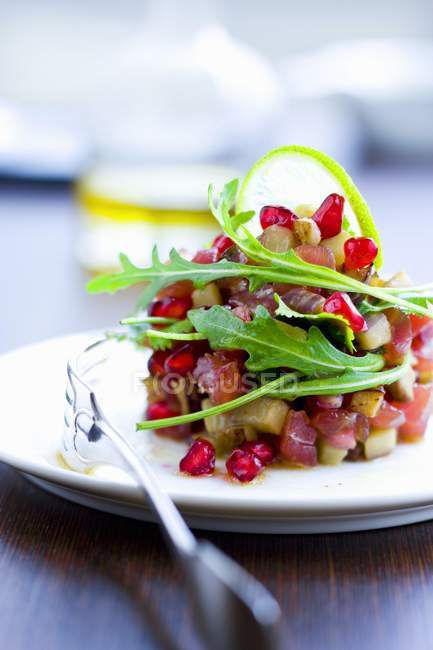 Tuna Tartare with pomegranate seeds and eggplant on white plate — Stock Photo