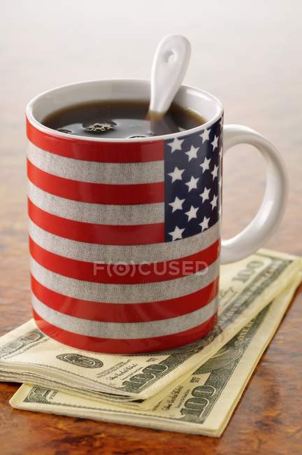 Cup of coffee with the American flag on it and dollar bills — Stock Photo