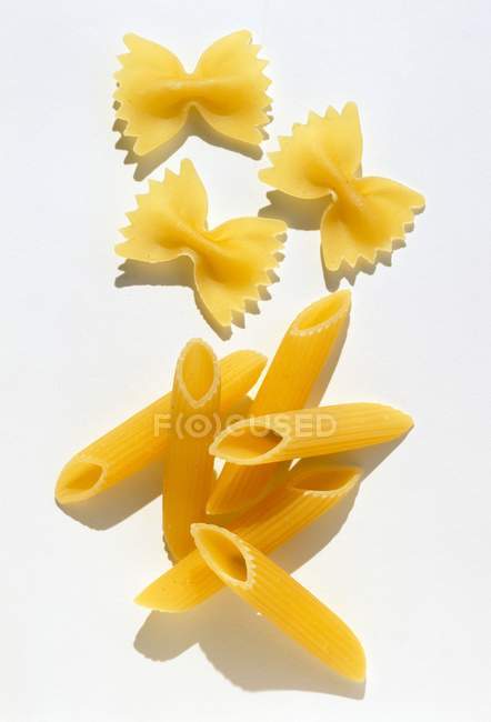 Trozos de pasta sin cocer de penne y farfalle - foto de stock