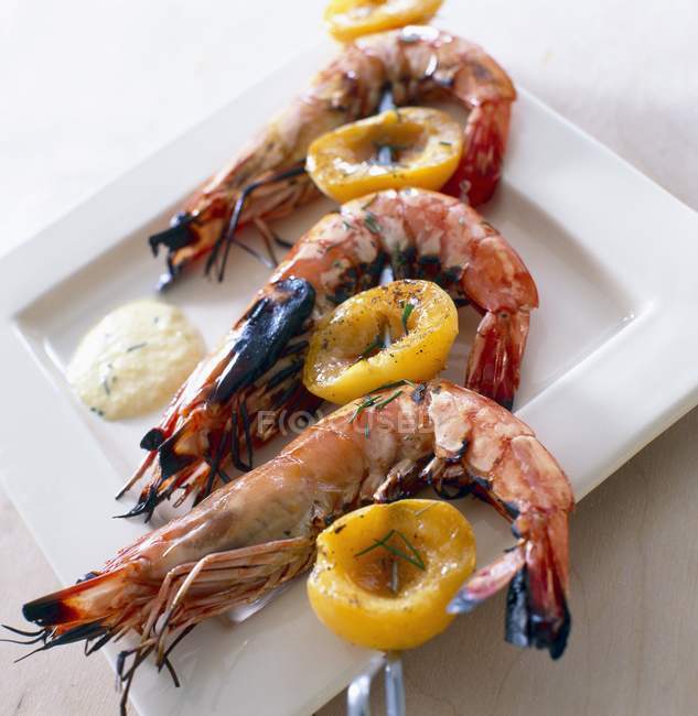 Gambas and apricot creole brochettes on white plate — Stock Photo