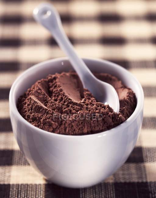 Vista de primer plano del cacao en polvo con una cuchara de cerámica en un tazón - foto de stock