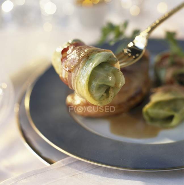Closeup view of pheasant supreme and little stuffed cabbages on a fork and on a plate — Stock Photo