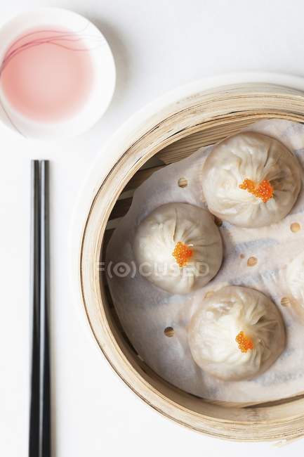 Closeup top view of steamed Chinese dumplings with fish roe in bamboo steaming basket with chopsticks and dipping sauce — Stock Photo