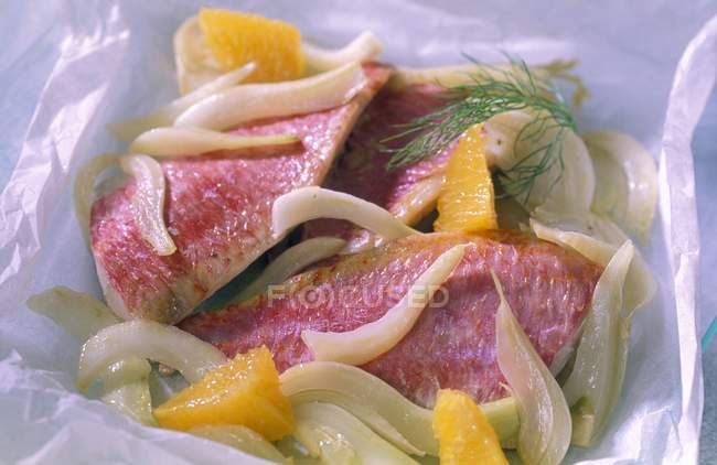 Filetes de pescado con verduras puestas sobre papel - foto de stock