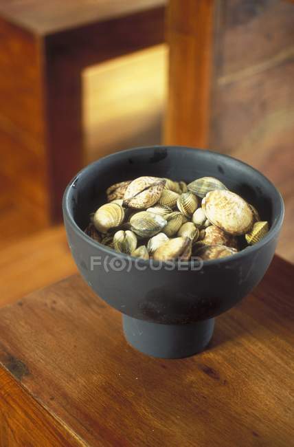 Closeup view of mussels in black bowl on wooden surface — Stock Photo