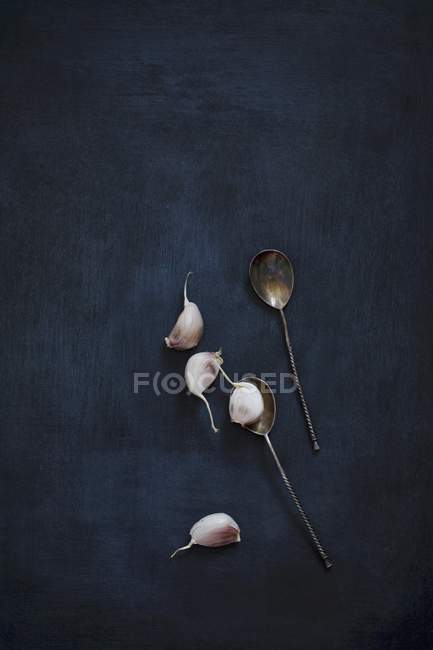 Garlic cloves and vintage silver spoons — Stock Photo