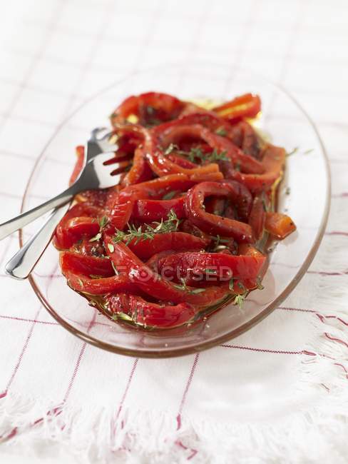 Poivrons rouges dans l'huile sur plaque de verre avec fourchettes — Photo de stock