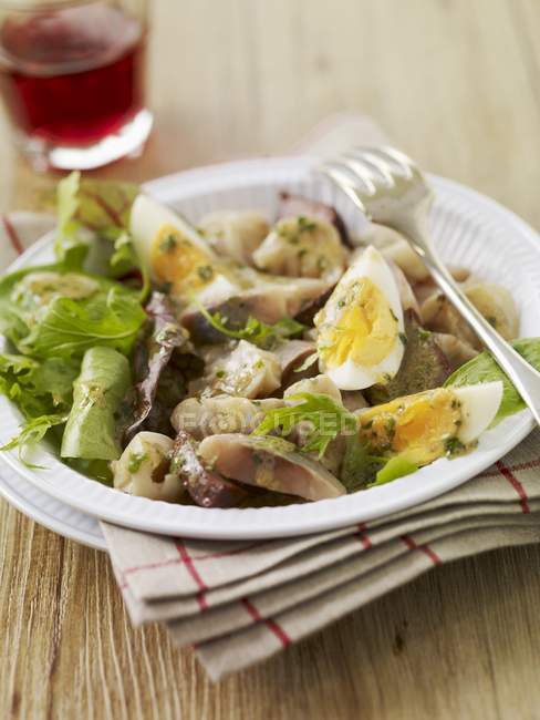 Salade Lyonnaise en plato blanco - foto de stock
