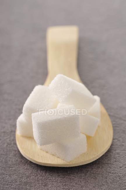 Morceaux de sucre sur cuillère en bois — Photo de stock