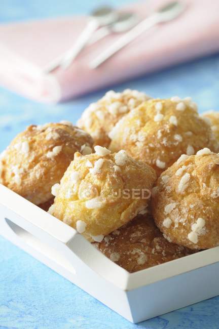 Chouquettes on white wooden crate over blue surface — Stock Photo