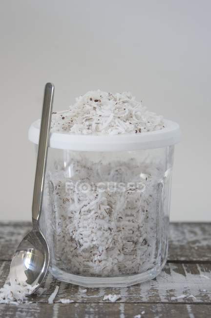 Closeup view of fresh coconut chips in plastic dish with spoon — Stock Photo