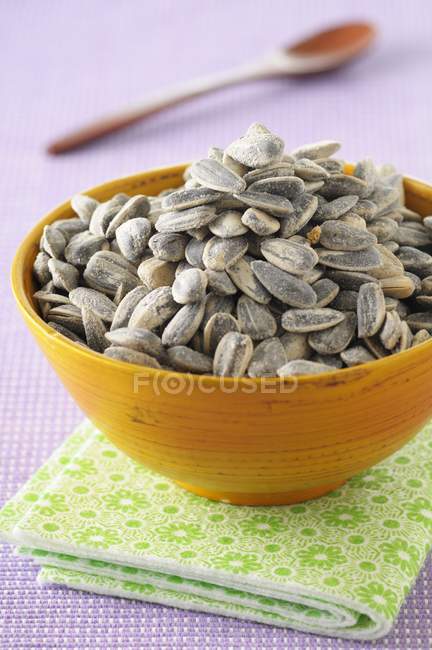 Bowl of sunflower seeds over green towel — Stock Photo