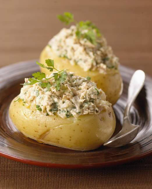 Stuffed potatoes on brown plate with spoon — Stock Photo