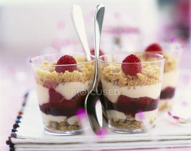 Closeup view of raspberry crumbles in glasses with spoons — Stock Photo