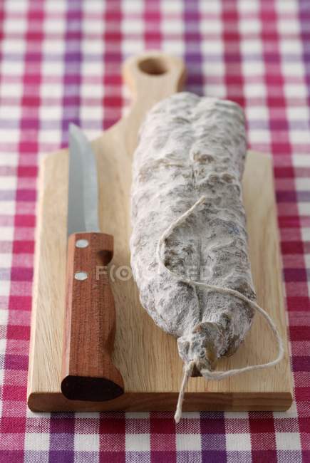 Dried sausage on chopping board — Stock Photo