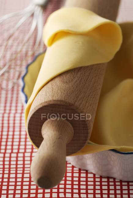 Closeup view of raw pastry on rolling pin and in baking dish — Stock Photo