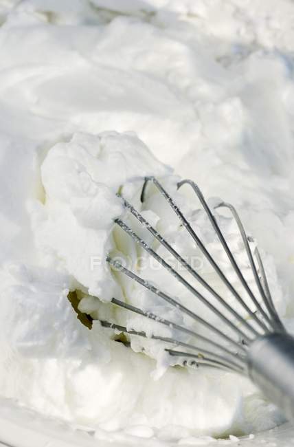 Vista close-up de claras de ovo batido e um batedor — Fotografia de Stock