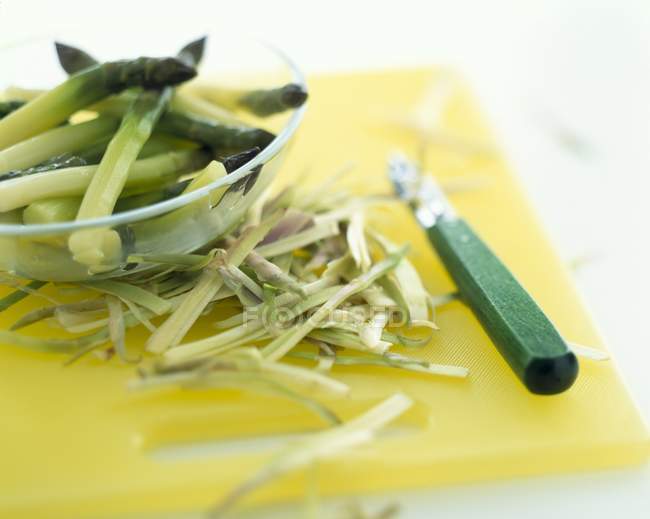 Peeling asparagi verdi su tagliere giallo — Foto stock