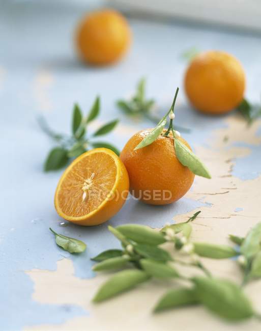 Naranjas frescas enteras y cortadas a la mitad - foto de stock