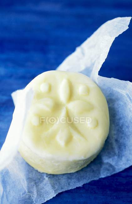 Closeup view of white chocolate cake on paper over blue surface — Stock Photo