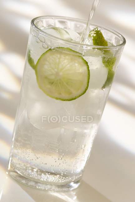 Closeup view of pouring sparkling water with slice of lemon — Stock Photo