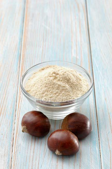 Chestnut flour in bowl with chestnuts — Stock Photo