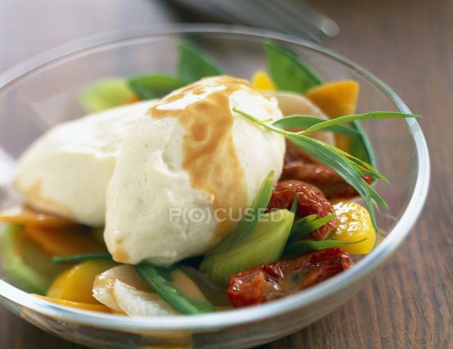 Quenelles with vegetables in glass plate  over wooden surface — Stock Photo