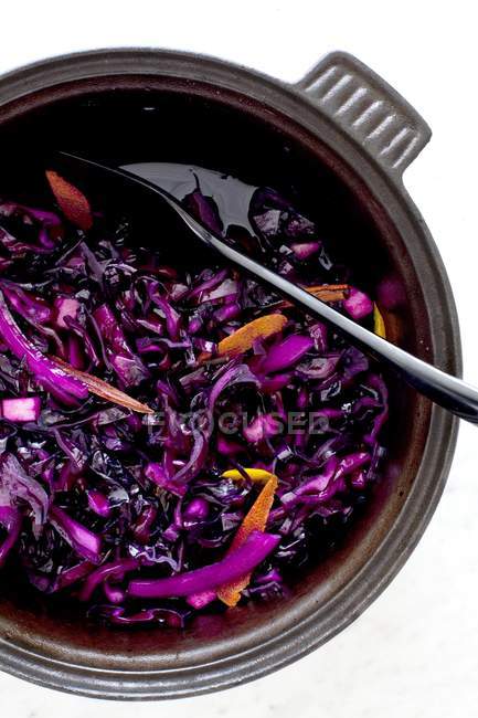 Red cabbage with orange peel  in bowl on white surface — Stock Photo