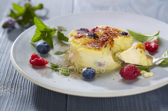 Closeup view of Creme brulee with berries and leaves on plate — Stock Photo