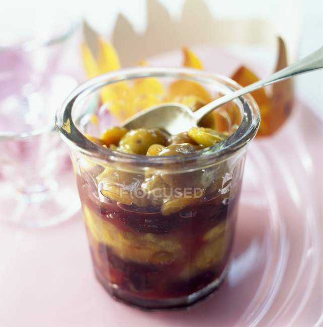 Alsatian stewed quetsch plums and mirabelle plums in glass jar with spoon — Stock Photo
