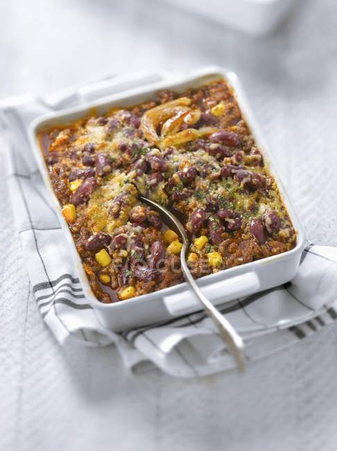 Chili con carne bake in white dish over towel — Stock Photo