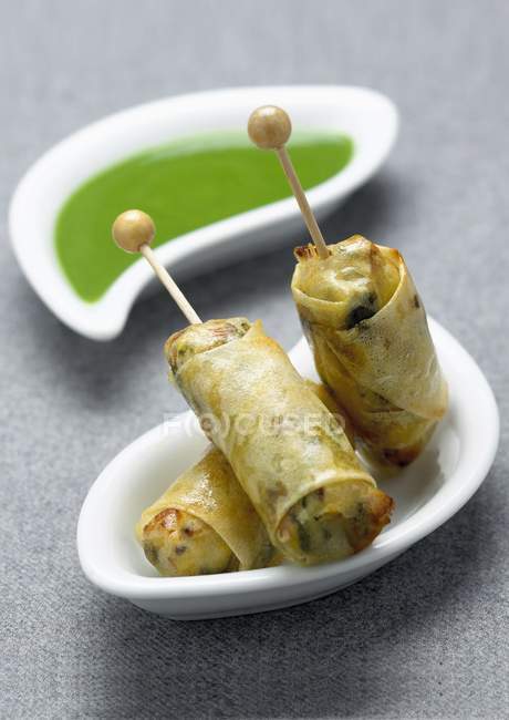 Closeup view of Nems with sticks and green sauce — Stock Photo