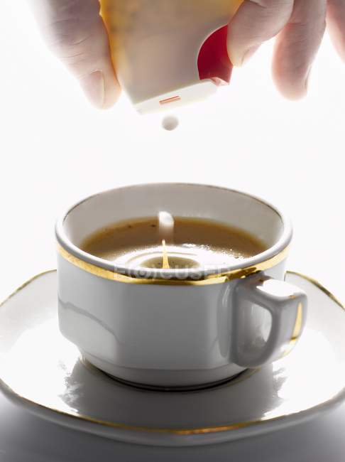 Vue rapprochée de la main en ajoutant un édulcorant artificiel à une tasse de café Espresso — Photo de stock