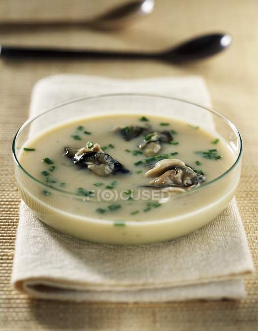 Oyster soup in glass plate over textile surface — Stock Photo