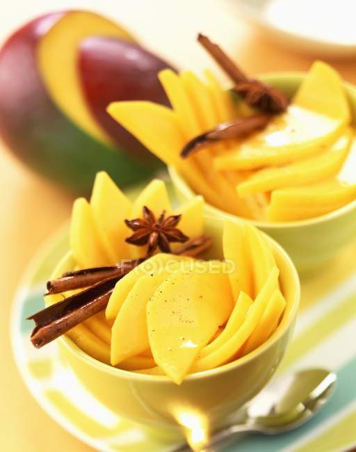 Vista de cerca de mangos frescos en rodajas con especias en cuencos - foto de stock