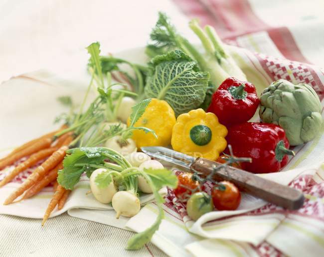 Assorted dwarf vegetables on table with towel and knife — Stock Photo