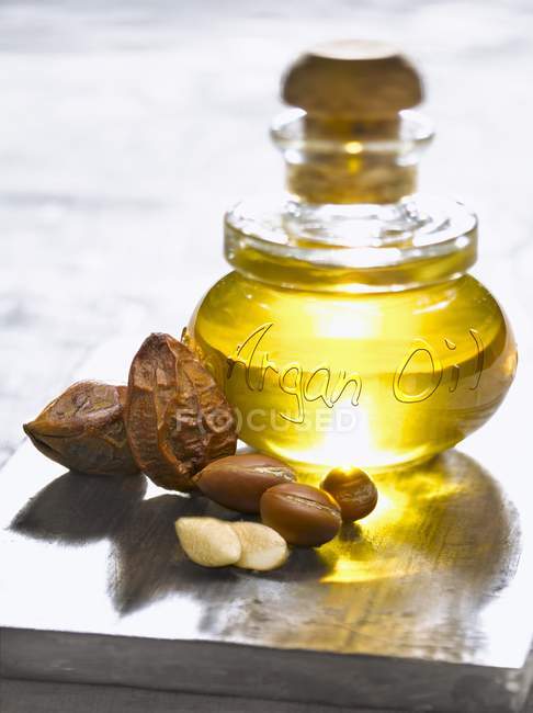 Closeup view of glass bottle with oil and Argan nuts — Stock Photo