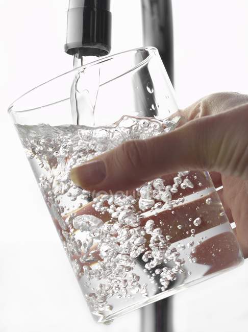 Llenar un vaso de agua del grifo - foto de stock