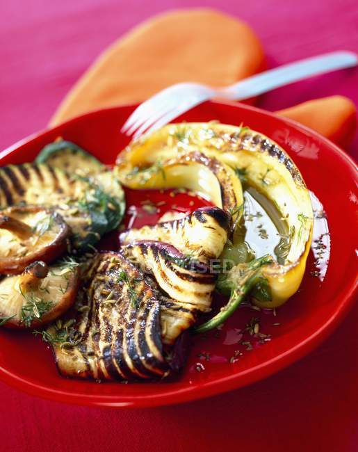 Grilled vegetables marinated in olive oil on red plate — Stock Photo