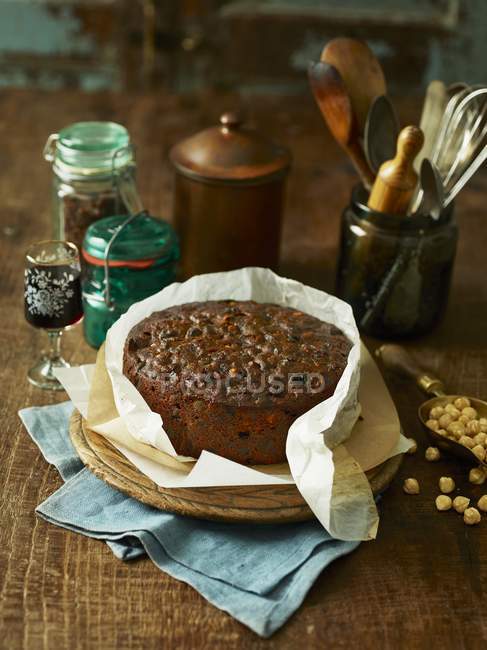Closeup view of fruit loaf in paper wrap on wooden board — Stock Photo