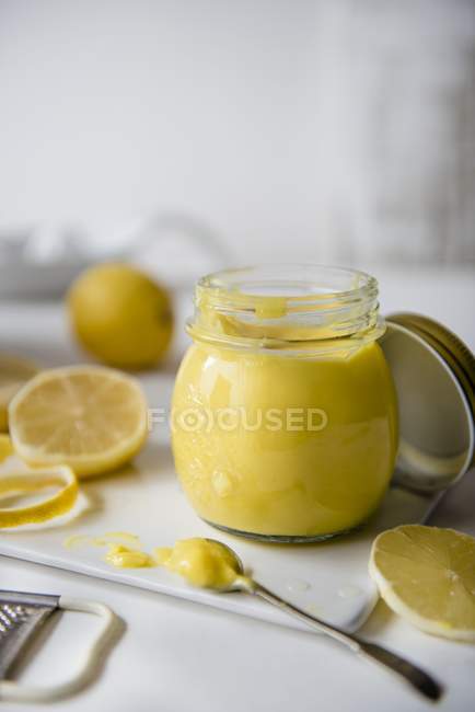 Vista de cerca de la cuajada de limón en un frasco con limones frescos - foto de stock