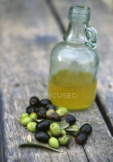 Aceitunas y botella de aceite de oliva - foto de stock
