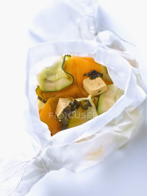 Calabacín, zanahoria, tofu, algas y salsa de soja cocidas en papel encerado - foto de stock