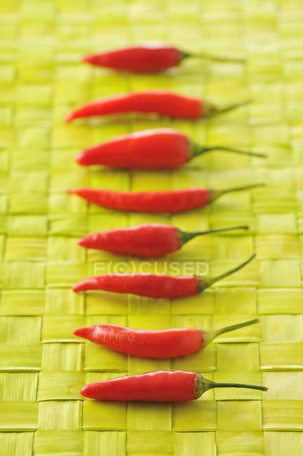 Row of pimentos on yellow straw mat — Stock Photo