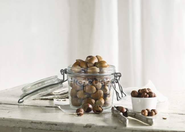 Hazelnuts in glass jar with nutcracker — Stock Photo