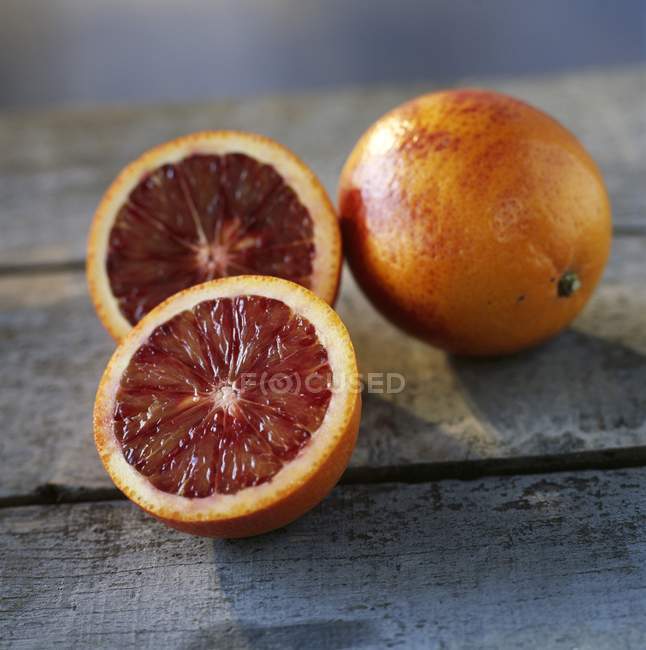 Naranjas de sangre enteras y cortadas a la mitad - foto de stock