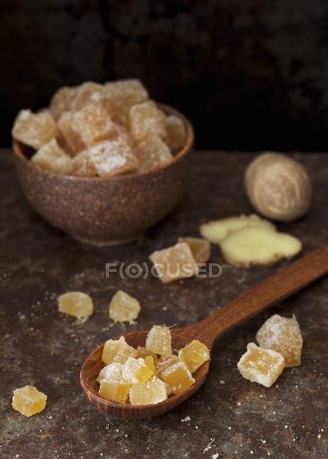 Closeup view of candied ginger in a bowl and on a wooden spoon — Stock Photo